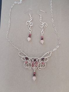 A beautiful rose quartz pink tourmaline and purple garnet neclace in elven style for you! Made to last with .925 Sterling silver wire and rose quartz, pink tourmaline and Madagascar purple garnet beads. The pendant is 2.5 inches wide and 2.5 inches long including the dangle on the bottom.  It's on an 18 inch chain, so the total length is just over 21 inches. The dangle earrings are 2.5 inches long and 5/8 inches wide. Pink Amethyst Wire Wrapped Jewelry, Elven Style, Purple Garnet, Quartz Pink, Necklace Ideas, Hessonite Garnet, Wrap Jewelry, Garnet Necklace, Necklace And Earrings Set