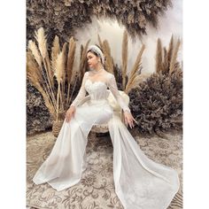 a woman sitting on top of a rug wearing a white dress and headpieces