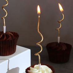 three chocolate cupcakes with candles sticking out of them