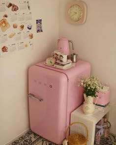 a pink refrigerator sitting next to a small table