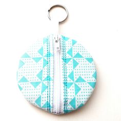 a blue and white zippered coin purse sitting on top of a white table next to a pair of scissors