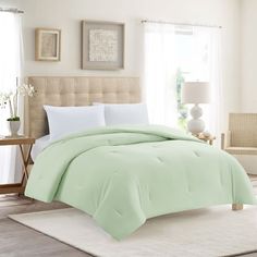 a bed with green comforter and pillows in a room