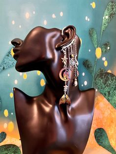 This enchanting mermaid moon ear cuff is sure to make a statement and bring out your inner magic! Silver ear cuff is embellished with a charm of two women in the moon, rainbow mermaid tail charm, iridescent drop crystals, seashell and starfish, and electroplated lava stone beads all dangling from silver and rainbow chains. This ear cuff is perfect for adorning pierced and non-pierced ears, and is lightweight and comfortable to wear. Lava Stone offers the following positive energies for the weare Handmade Dangle Cartilage Earrings For Party, Celestial Single Earring For Party, Unique Single Cartilage Earring For Party, Whimsical Silver Single Ear Cuff, Bohemian Moon Charm Jewelry For Party, Handmade Dangle Ear Cuff For Festivals, Whimsical Moon Charm Dangle Jewelry, Whimsical Dangle Moon Charm Jewelry, Whimsical Dangle Jewelry With Moon Charm