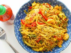 a blue bowl filled with noodles and vegetables