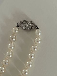 Akoya cultured pearl necklace with a slight fall (between 7.80 and 7.30 mm). Art Deco style square clasp in white gold (18k) set with old-cut and 8/8-cut round diamonds. Total weight of diamonds: approximately 0.50 ct. Length: 43 cm. Clasp: 15 x 9 mm. Gross Weight: 35.60 g Further information : We issue an invoice as well as a certificate of authenticity established by our qualified gemologist (LFG Paris). Our photos are not reworked and are taken in a natural light environment. We can send you Classic Jewelry With Sterling Silver Clasp, Fine Jewelry Akoya Pearl Necklace With 17 Jewels, Elegant Diamond Jewelry With Box Clasp, Timeless Wedding Jewelry With Box Clasp, Timeless Wedding Jewelry With Clasp, Formal Vintage Akoya Pearl Necklace, Timeless Rectangular Necklace For Formal Occasions, Classic Round Pearl Necklace With 17 Jewels, Classic Silver Pearl Necklace With 17 Jewels