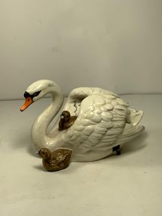 a white swan figurine sitting on top of a table next to a brown duck