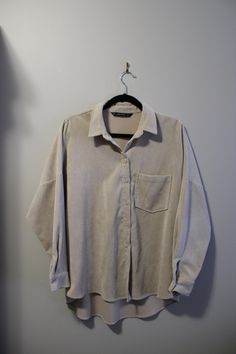 This Zara blouse is a over-sized work shirt style top, in a beige corduroy. Oversized Beige Blouse With Button Closure, Oversized Neutral Blouse For Fall, Oversized Cream Long Sleeve Shirt, Corduroy Button-up Tops For Workwear, Oversized Collared Corduroy Top, Oversized Corduroy Tops For Spring, Relaxed Fit Corduroy Workwear Tops, Relaxed Fit Corduroy Tops For Workwear, Shirt Style Tops