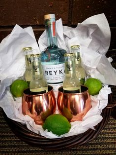 two copper cups with limes and bottles in them