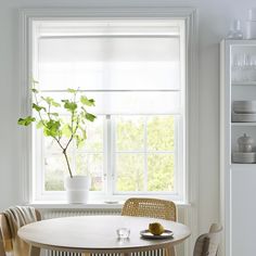 a white table with chairs and a potted plant in the window sill next to it