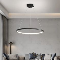 a living room filled with furniture and a round light fixture hanging over the couches