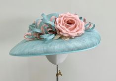 "A beautiful classic duck egg aqua blue wide brimmed sinamay straw hat with hints of pink.  This gorgeous headpiece is made using traditional straw sinamay, and has a combination of loops of the same straw in duck egg blue and the softest pale pink peach.  The loops continue around the entire crown of the hat, adding interest from all angles. Central to this design is an exquisite silk dupion rose in pale pink peach that sits just off centre, giving this headpiece a truly glamorous and elegant f Light Blue Summer Hat For Races, Light Blue Summer Hats For Races, Blue Sinamay Hat For Summer, Light Blue Hat For Royal Ascot Races, Turquoise Hats For Spring Races, Turquoise Spring Racing Hat, Blue Straw Hat For Spring, Spring Wedding Turquoise Hats, Blue Summer Hats With Handmade Flowers