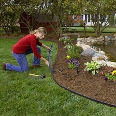 a woman kneeling down in front of a pond with flowers and plants growing out of it