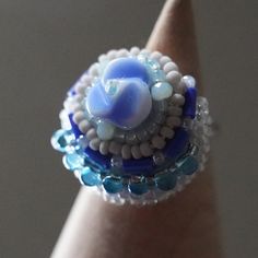 When I make a ring, I first decide on the main bead. If the beads are embroidered in a way that enhances them, the result is a ring that is colorful and lively, almost as if it is talking. If you wear such a ring when you go out, you will be able to spread the chatter even further. and the chatter will spread even more. This is a chatty ring made with the hope that this will happen. Size of the decorative part: about 1 in (2.5 cm) in diameter Size of the ring: free (you can adjust it by yourself Handmade Unique Crystal Open Ring, Multicolor Handmade Open Ring, Blue Beaded Rings For Gifts, Blue Beaded Rings As A Gift, Blue Rings With Colorful Beads For Gift, Handmade Blue Crystal Ring With Unique Style, Blue Beaded Rings As Gift, Blue Beaded Rings As Gifts, Turquoise Beaded Rings As A Gift