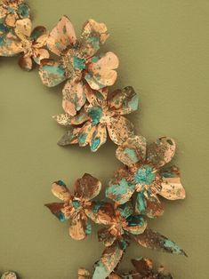 some flowers are hanging on the wall in front of a green wall with brown and blue paint