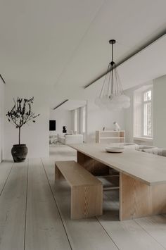 a large white room with wooden flooring and a long table in the center surrounded by chairs