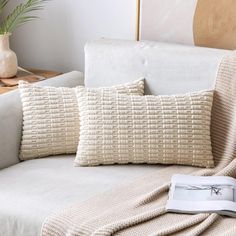 a white couch with two pillows and a book on the armrest next to it