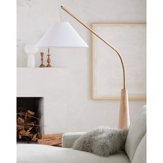 a living room with a white couch and a wooden floor lamp next to a fire place