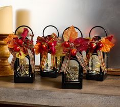 four small lanterns with fall decorations on them