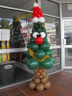 a christmas tree made out of balloons in front of a store