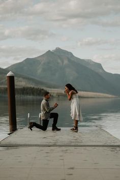 a man kneeling down next to a woman on a dock