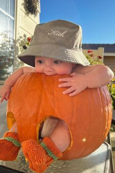 a baby in a hat and mittens is sitting on a pumpkin