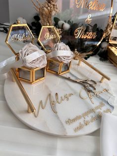 two wedding rings are sitting on top of a white plate with gold lettering and flowers