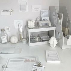 a white desk topped with lots of office supplies and items on top of each other