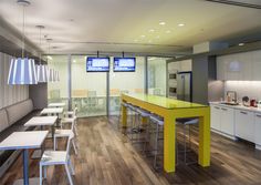 an empty kitchen with yellow counter tops and white chairs in front of a television screen