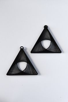 two black triangle shaped pendants on a white surface