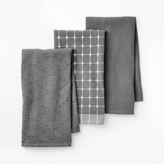 three gray and white towels on top of each other, one with a square pattern