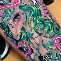 a colorful unicorn tattoo with stars and hearts on it's arm, next to a black shoe