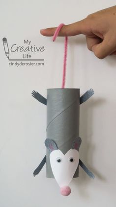 a hand holding a roll of paper with a mouse hanging from it's side