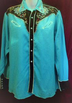 A Beautiful Blue , Black 1950s Western Rayon  Shirt, Ranch wear Shirt with Embroidered front and collar also this great shirt has pearl snap buttons down the front and on the cuffs and smiley pockets. Great shirt for all you Vintage Lovers  at any event. Label  N/A Measurements :  Approximately  Chest      -   44  Inches Length    -   27.5  Inches  Collar      -    15 Inches Condition     -   Good Vintage Condition  Stain at the back of shirt and also collar please check all pictures carefully thank you.  We ship Worldwide PLEASE request a shipping quote for all purchases outside the UK.    THANK YOU. Also don't forget to check out all my other Vintage Treasures. Western Style Blue Tops With Buttons, Western Blue Button-up Top, Blue Western Shirt With Button Closure, Classic Blue Tops For Rodeo, Traditional Fitted Blue Shirt, Traditional Blue Fitted Shirt, Blue Rodeo Top With Snap Buttons, Vintage Blue Embroidered Blouse, Blue Embroidered Collared Shirt