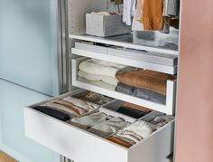 an open drawer in a closet filled with clothes