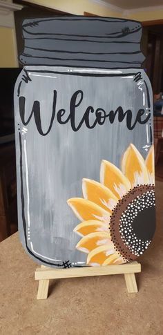 a painted mason jar sitting on top of a wooden easel with a sunflower