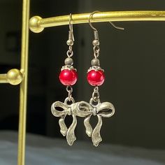 Crafted from my grandmother, Susie, these earrings feature moody red charm and bow. Add a touch of timeless elegance to your jewelry collection with these beautifully crafted earrings. They make a perfect gift for someone special or a delightful treat for yourself. Details: Second image is more accurate coloring Materials: Stainless Steel, red glass pearls Charm: Bow Design: Handmade Style: Elegant and versatile Care Instructions: To keep your earrings looking their best, gently clean with a sof Elegant Christmas Drop Earrings, Elegant Christmas Jewelry With Matching Earrings, Elegant Christmas Jewelry With Dangle Shape, Red Christmas Earrings For Formal Occasions, Red Earrings For Christmas Formal Occasion, Red Earrings For Christmas Formal Events, Red Jewelry For Pierced Ears As A Gift, Elegant Valentine's Day Earrings For Festive Occasions, Valentine's Day Bow Jewelry Gift