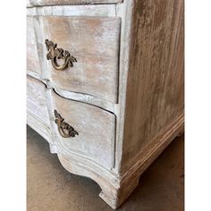 an old white dresser with brass handles