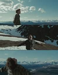 a man standing on top of a snow covered slope next to mountains with his arms outstretched