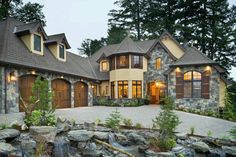 a large house with a waterfall in the front yard and two garages on each side