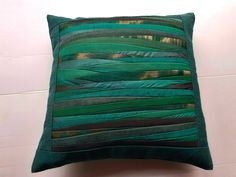 a green pillow sitting on top of a white tile floor next to a tiled wall