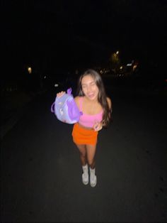 a girl in an orange skirt holding a purple purse and smiling at the camera with her hands on her hips