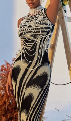 a woman in a black and white dress posing for the camera with her hand on her head