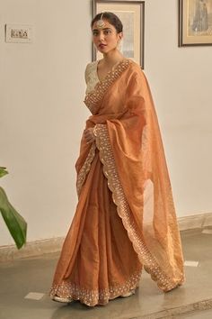 Rust saree with scallop trimmed, floral hand embroidery. Paired with a cream blouse with stripe pattern. - Aza Fashions Festive Pre-draped Saree With Embroidered Border In Cotton Silk, Festive Cotton Silk Pre-draped Saree With Embroidered Border, Traditional Cotton Silk Pre-draped Saree With Embroidered Border, Elegant Cotton Silk Blouse Piece With Embroidered Border, Cotton Silk Saree Blouse With Embroidered Border, Fitted Chanderi Pre-draped Saree With Embroidered Border, Fitted Pre-draped Chanderi Saree With Embroidered Border, Eid Saree Blouse With Embroidered Border, Reception Embroidered Tissue Silk Pre-draped Saree