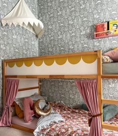 a bunk bed with curtains and pillows in a room that is decorated with wallpaper