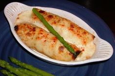 a white plate topped with fish and asparagus on top of a blue table