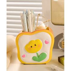 a yellow and white toaster shaped pen holder holds pens, pencils, and other office supplies