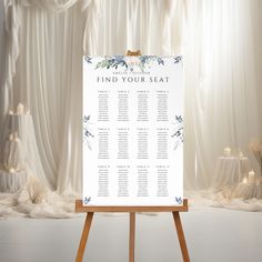 an easel with a seating chart on it in front of a curtained backdrop