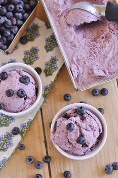 two bowls filled with ice cream next to blueberries