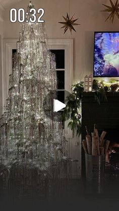 a large christmas tree in the middle of a living room next to a tv and fireplace