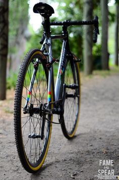 a bike parked on the side of a dirt road in front of trees and grass